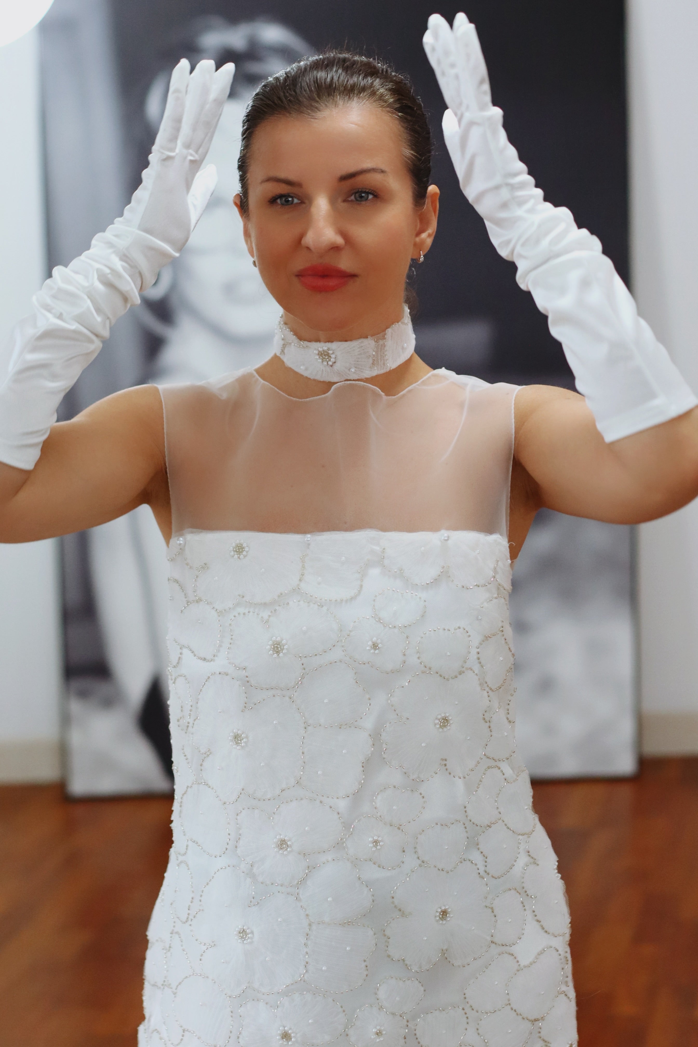 Woman wearing a white lace dress and gloves in an indoor setting