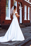 A young bride wearing Velo Bianco minimalistic off the shoulder satin wedding dress with buttoned back paired with short elegant wedding veil and white bridal heels. Manchester City hall wedding outfit for the modern bride.