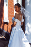 A young bride wearing Velo Bianco minimalistic off the shoulder satin wedding dress with buttoned back paired with short elegant wedding veil and white bridal heels. Manchester City hall wedding outfit for the modern bride.
