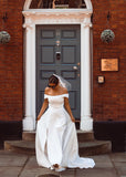 A young bride wearing Velo Bianco minimalistic off the shoulder satin wedding dress with buttoned back paired with short elegant wedding veil and white bridal heels. Manchester City hall wedding outfit for the modern bride.