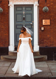 A young bride wearing Velo Bianco minimalistic off the shoulder satin wedding dress with buttoned back paired with short elegant wedding veil and white bridal heels. Manchester City hall wedding outfit for the modern bride.