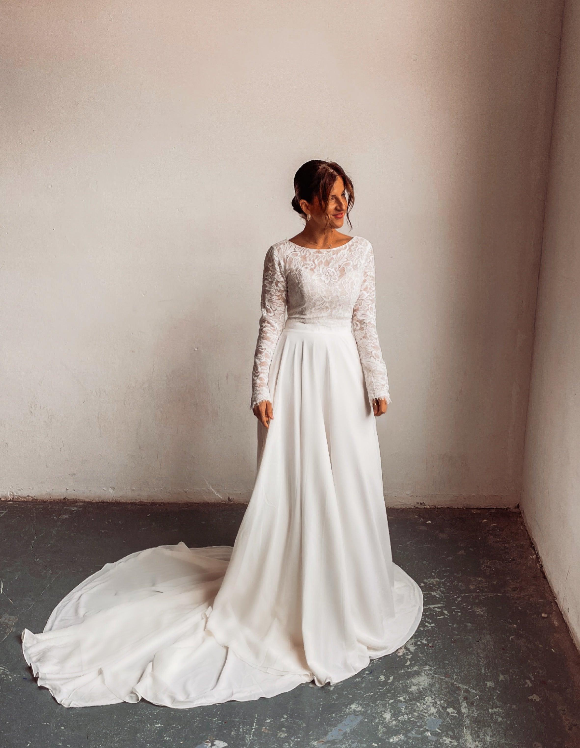 A bride wearing a two piece bohemian lace wedding dress. The ivory lace top is long sleeve and the chiffon skirt is high waisted. This two piece lace dress is perfect for boho themed weddings, rustic weddings and elopements.