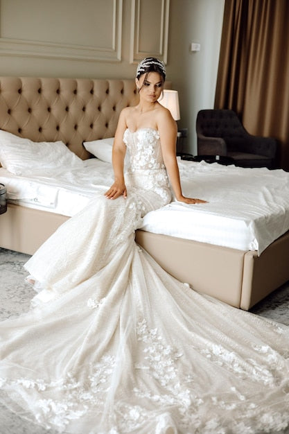 a woman in a wedding dress sits on a bed
