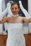 Woman wearing a white lace dress and gloves in an indoor setting