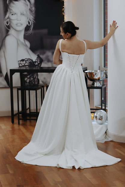 Introducing Hope - a newest addition to our luxury crepe wedding dress collection. &nbsp;Basque waist wedding dresses are leading the bridal fashion trends this year, with their signature V-shaped waistline captivating brides everywhere. Our luxury crepe basque waist bridal gown beautifully blends timeless charm with contemporary elegance, designed to make any bride feel exquisite. Crafted from premium crepe fabric, this gown offers a smooth, graceful drape that complements its striking silhouette.