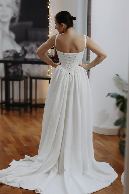 Introducing Hope - a newest addition to our luxury crepe wedding dress collection. &nbsp;Basque waist wedding dresses are leading the bridal fashion trends this year, with their signature V-shaped waistline captivating brides everywhere. Our luxury crepe basque waist bridal gown beautifully blends timeless charm with contemporary elegance, designed to make any bride feel exquisite. Crafted from premium crepe fabric, this gown offers a smooth, graceful drape that complements its striking silhouette.