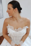 Our luxury satin basque waistline wedding dress embodies the best of this trend, blending timeless romance with a modern edge. The gown’s fitted bodice features a lace-up corset that creates a beautifully sculpted silhouette while offering customizable support. Delicate lace trim along the neckline adds a soft, feminine touch, framing the shoulders and décolletage with elegant detail.